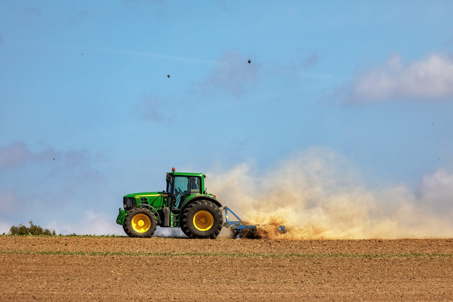 Farmer tilling the soil with disc harrow, Germany